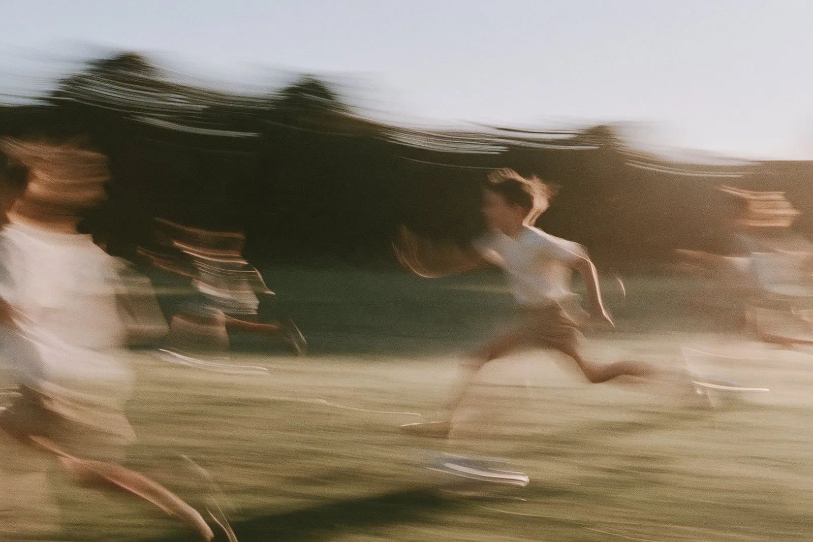 Children running across a field, blurred with movement.