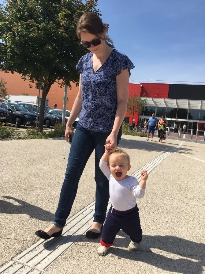 Kate, years ago, walking a toddler by the hand along a sunny footpath.